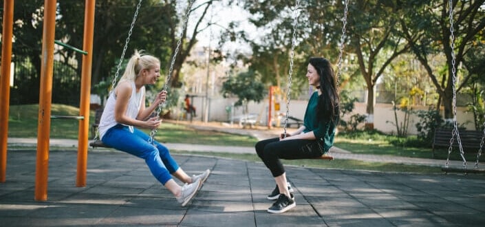 Two women sitting in park swings