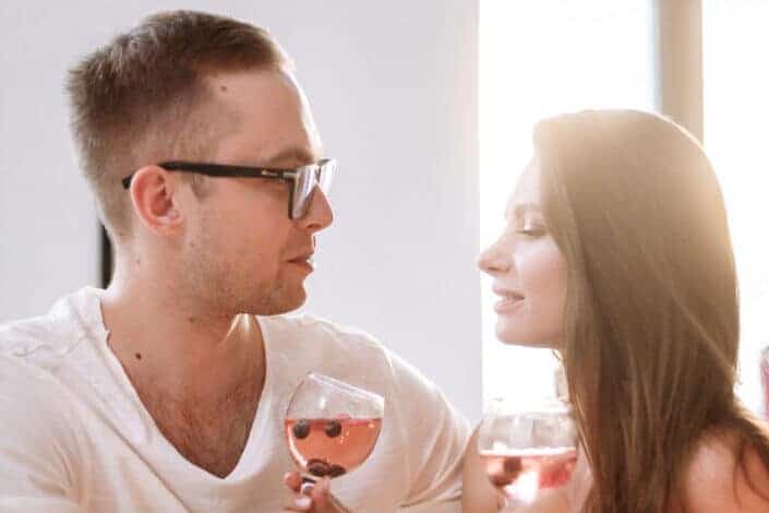 A couple holding wine glasses while looking at each other