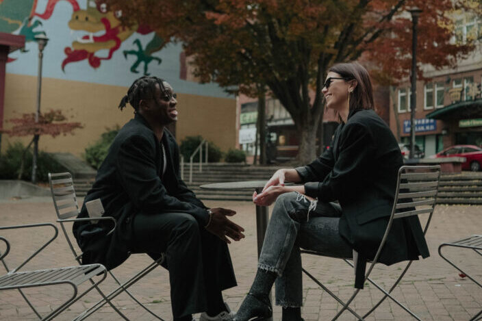 A man and woman sitting on a park while having a conversation