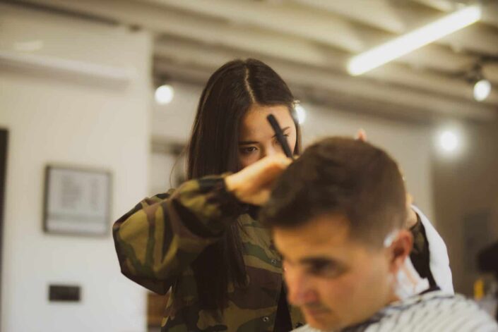 A woman trimming a man's hair