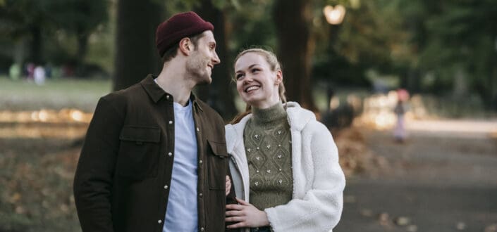 Cheerful young couple standing in park and smiling