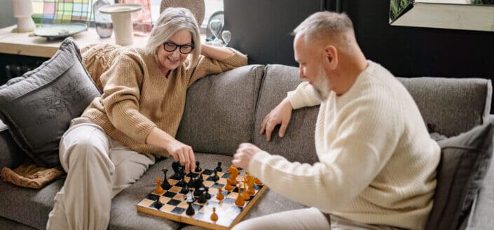 Couple sitting on a couch while playing chess