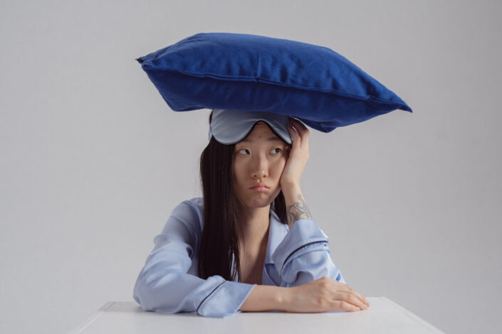 Woman in a sleeping outfit with pillow on her head