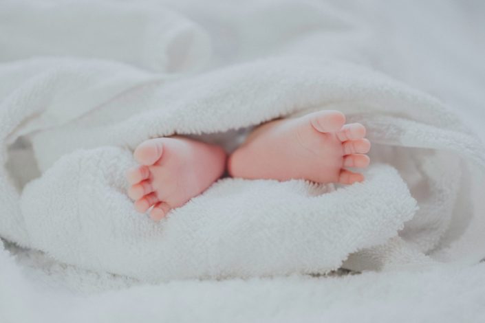 Delicate baby feet, wrapped in a white towel.