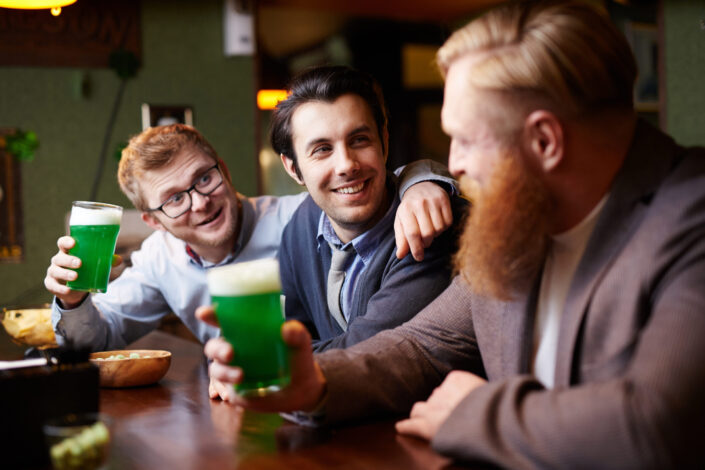 Three office people happily drinking a green alcoholic drink