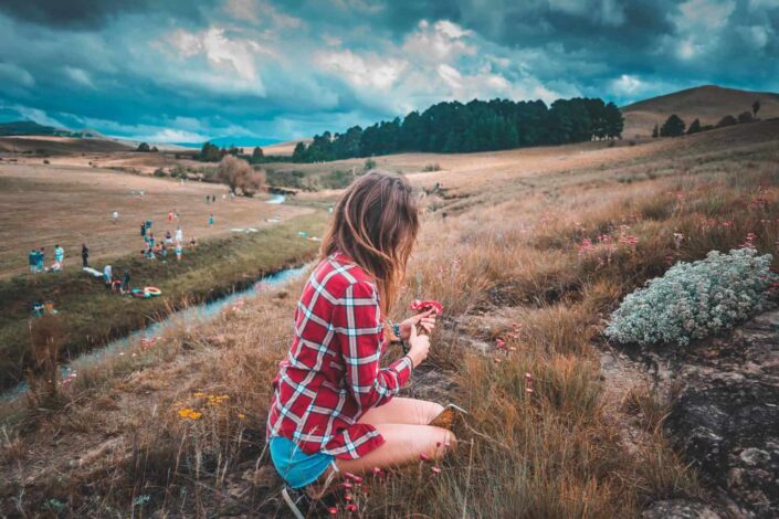 Girl picking flowers on a hill.