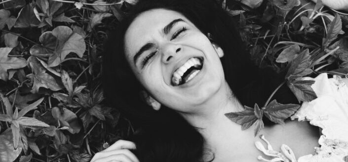 grayscale-photo-of-woman-laughing-while-sleeping-on-plants-stockpack-pexels