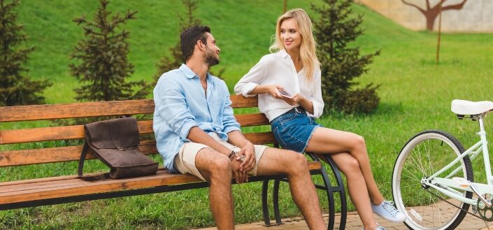 Couple having conversation while resting on bench after walk in park