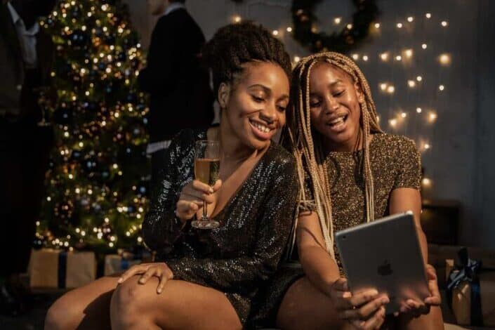 two women smiling in front of an iPad