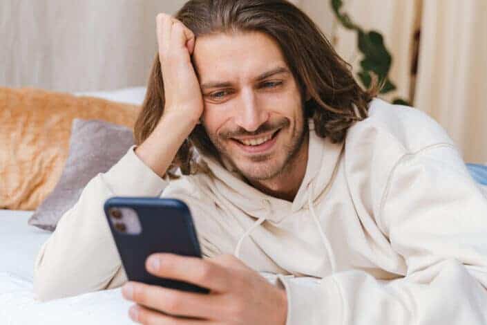 Man lying on a bed while texting