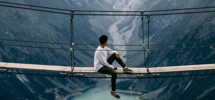 Man sitting on a hanging bridge