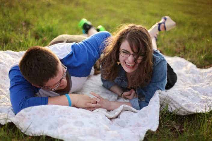 Couple lying on white blanket on grass