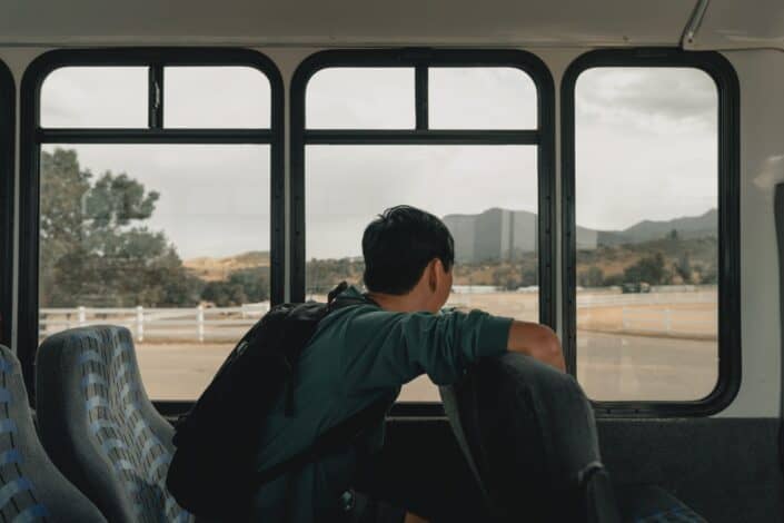A young man staring outside the window bus