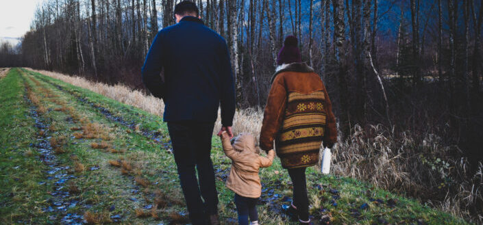 couple walking their child near forest