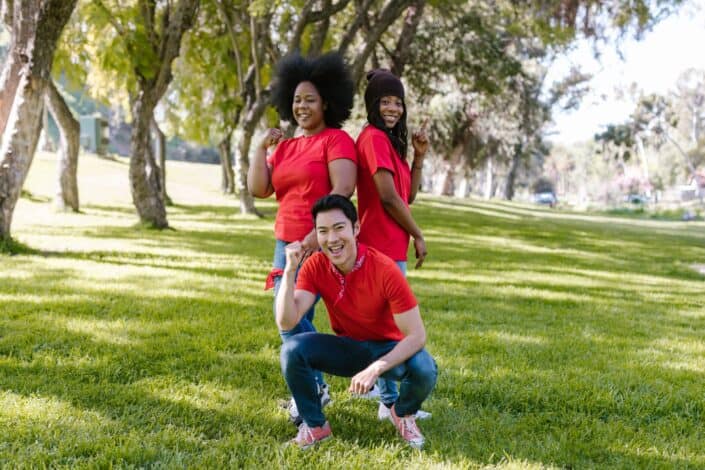 man-in-red-crew-neck-t-shirt-sitting-beside-two-women-standing-