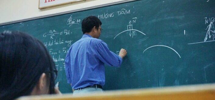 physics teacher writing on a board