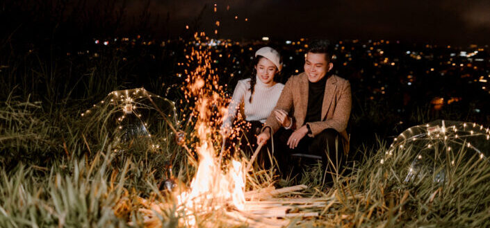 happy couple basking near bonfire in evening