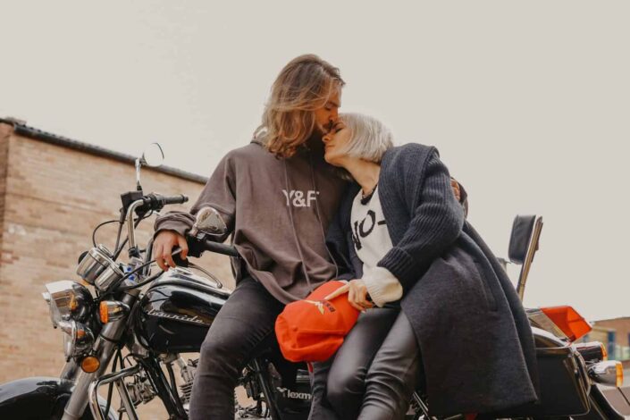 A man kissing a woman on the forehead while sitting on a motorcycle