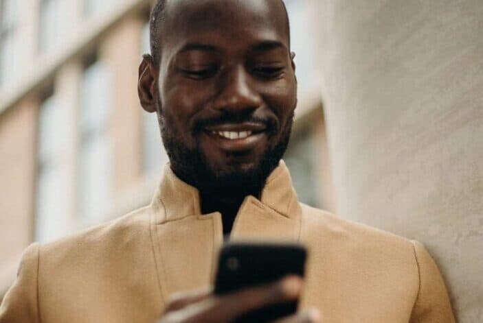 A man smiling at his phone while he's holding it