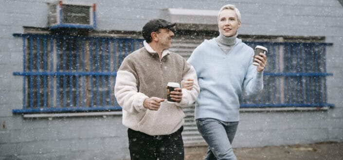 Couple in sweaters holding coffee walking on the streets