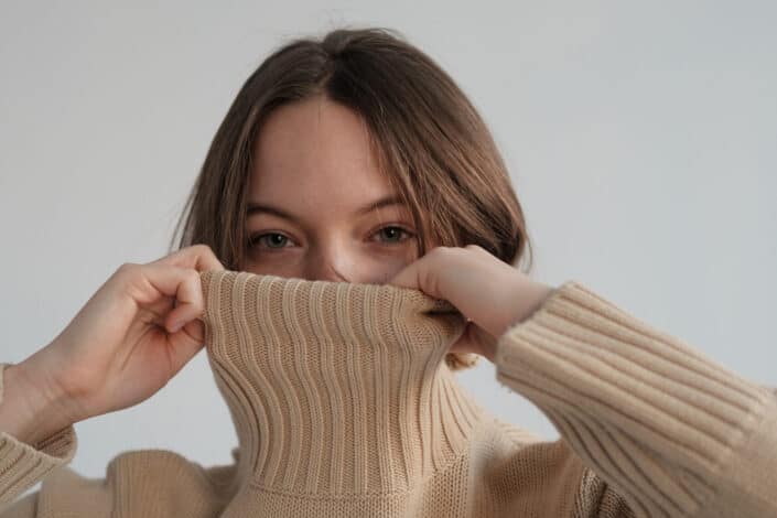 Woman covering her face with her turtle neck blouse
