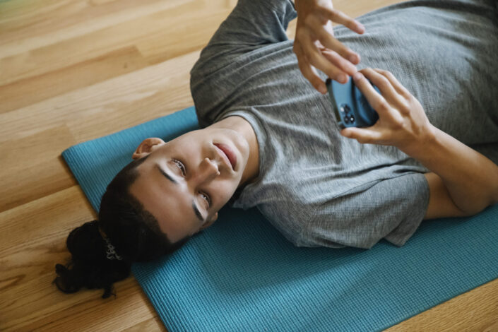 Young Man Lying on Mat With Phone
